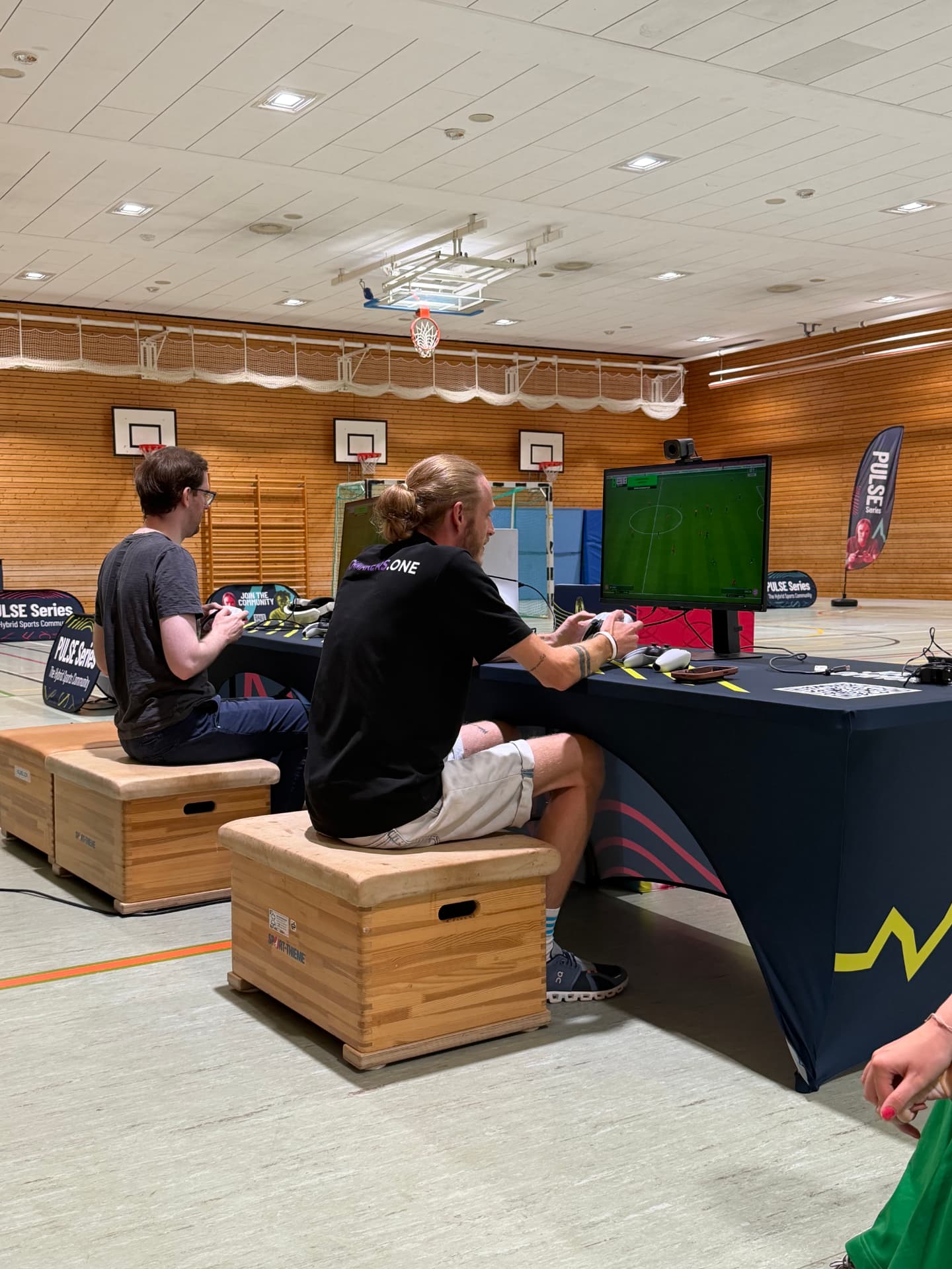Zwei Spieler im EA SPORTS FC Duell beim PULSE Tryout in Oberhaching, umringt von PULSE Bannern